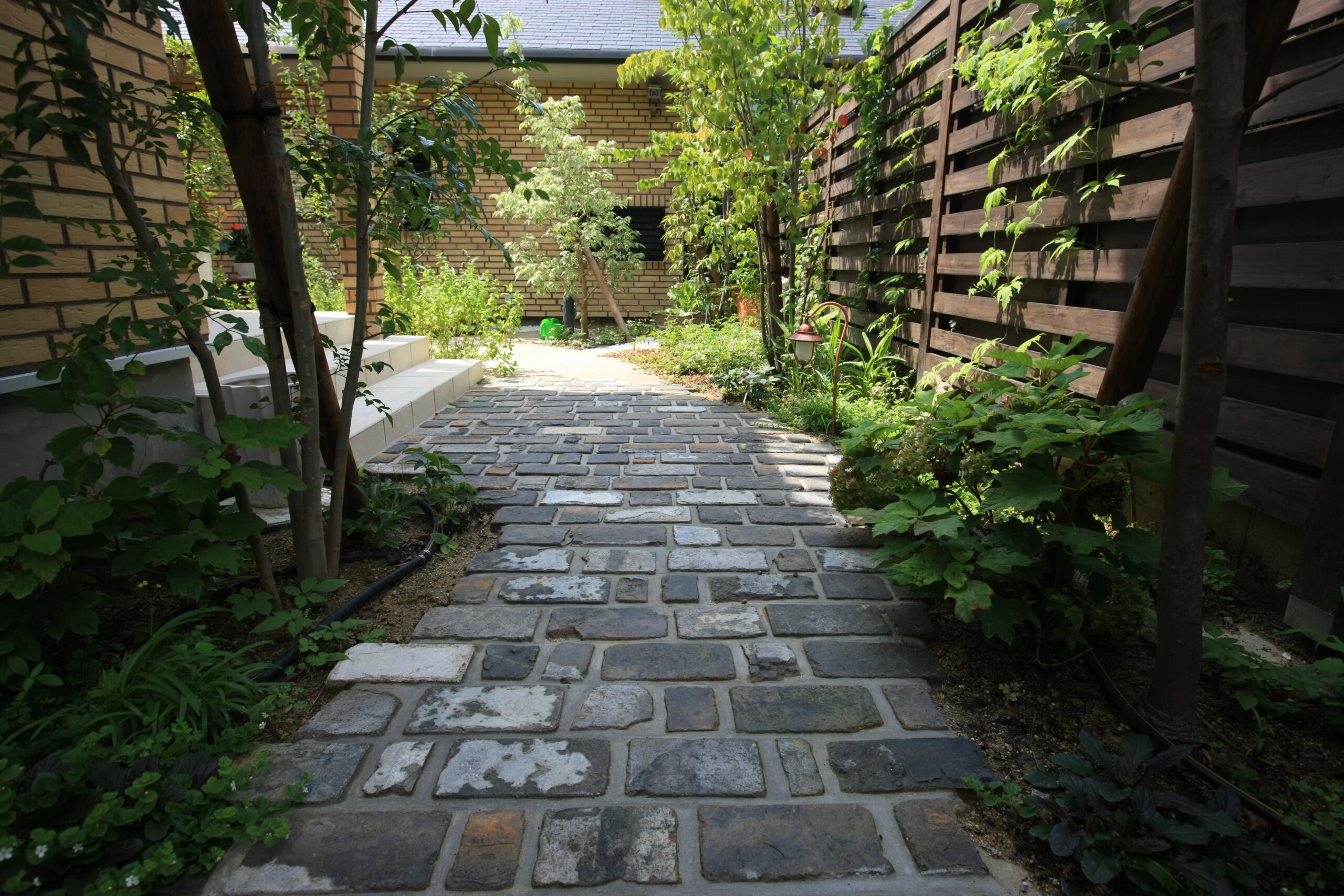 アンティークレンガと植栽が調和するアプローチ